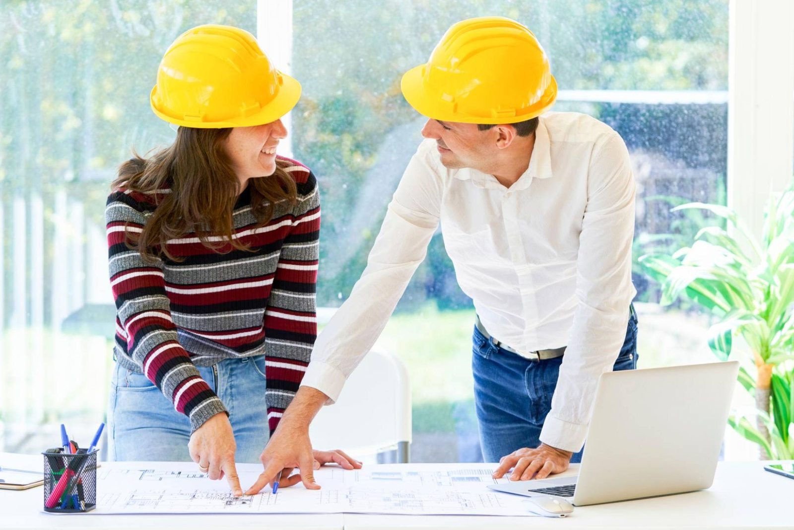 Dos compañeros con casco estudiando unos planos